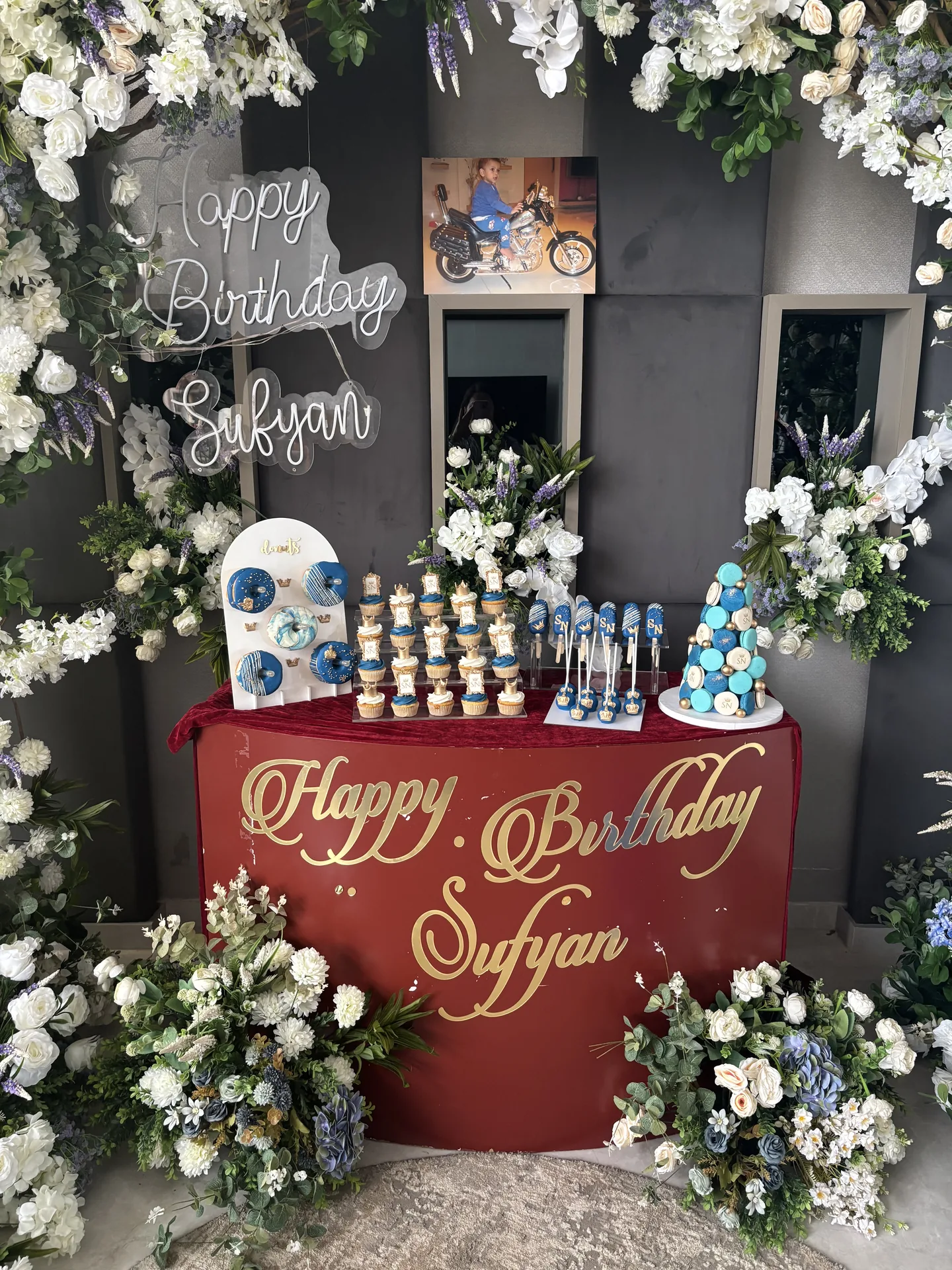 Birthday dessert table setup with cupcakes, doughnuts and coordinated blue and gold desserts