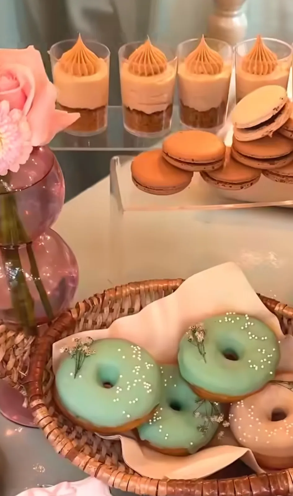 Doughnuts, macarons, dessert cups and themed cookies arranged for a dessert table