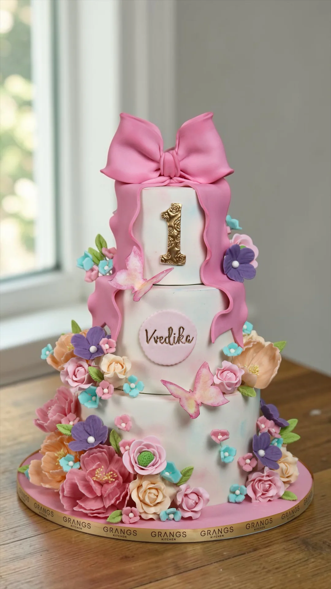 Elegant first birthday cake with pink bow, butterflies and flowers
