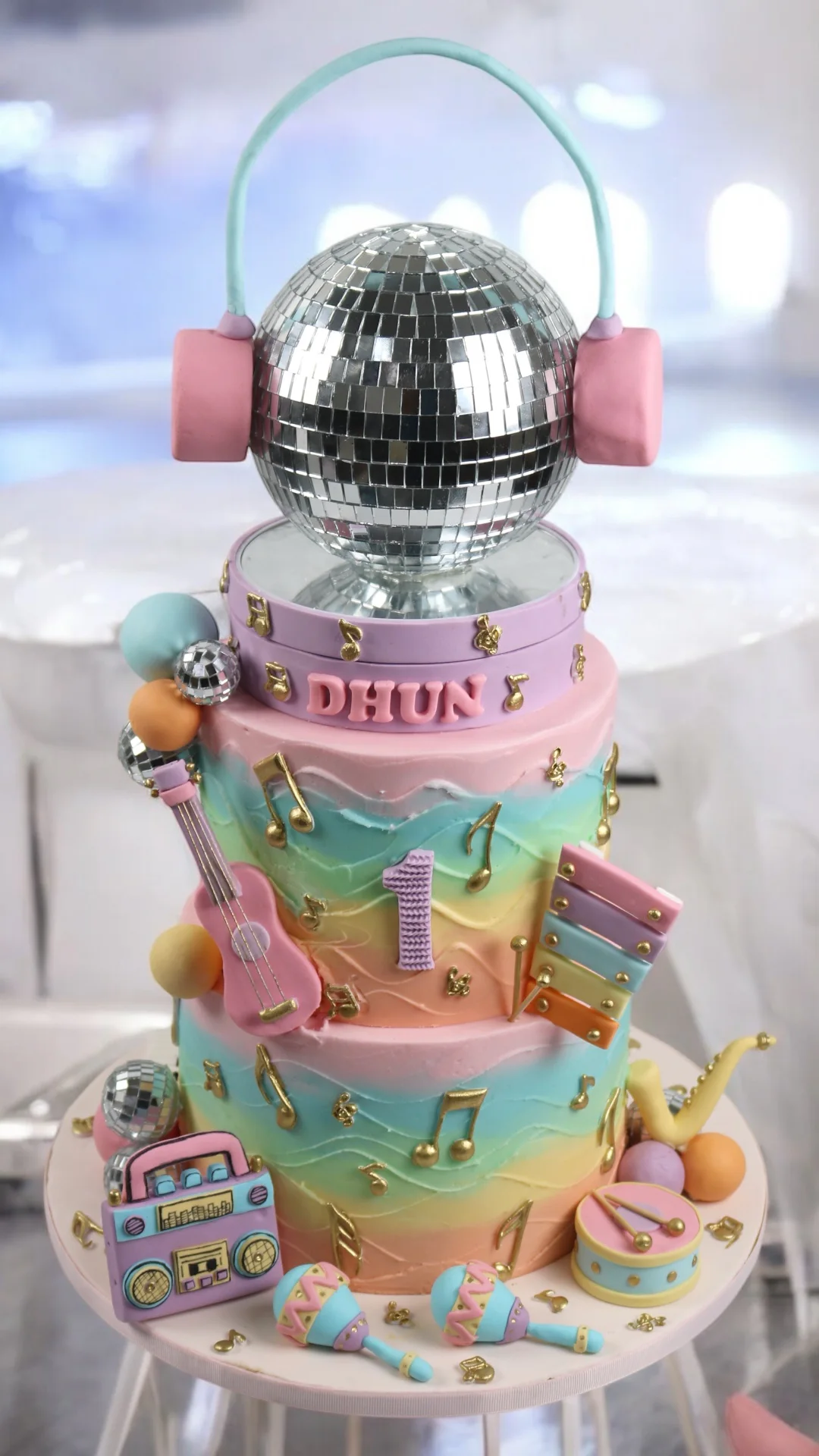 Colourful music-themed first birthday cake with disco ball and instruments