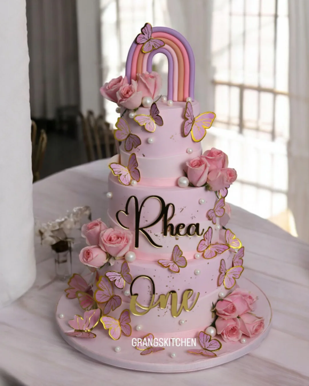 Pink rainbow and butterfly first birthday cake with roses