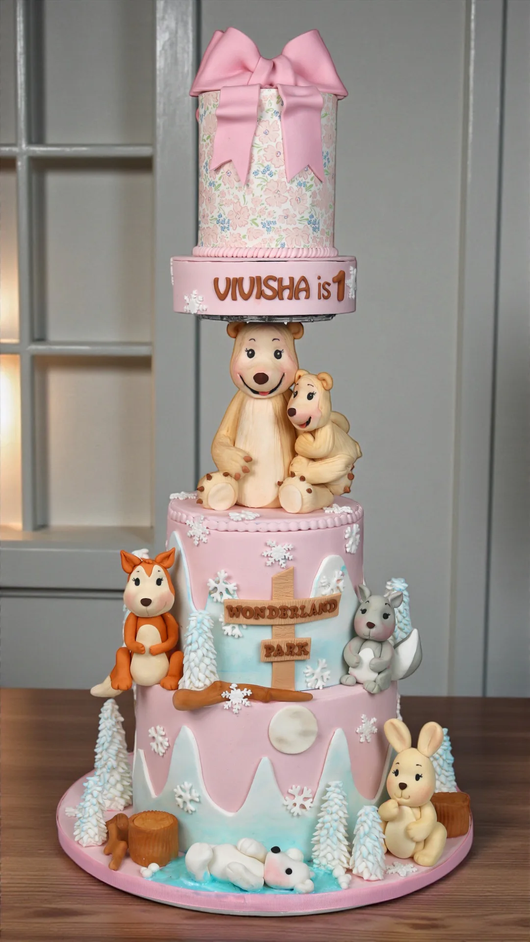 Pink winter-animal first birthday cake with bears and woodland figures