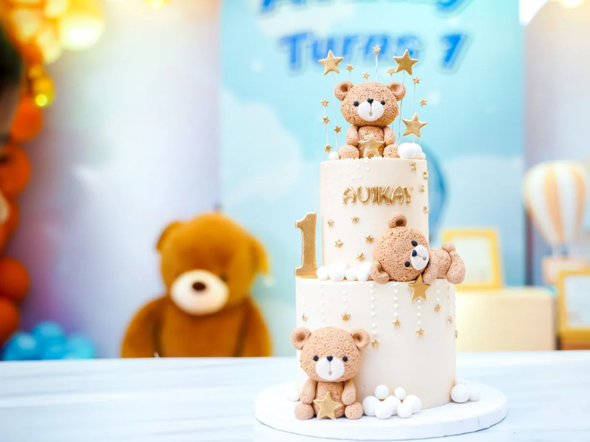 Teddy bear first birthday cake with blue party backdrop