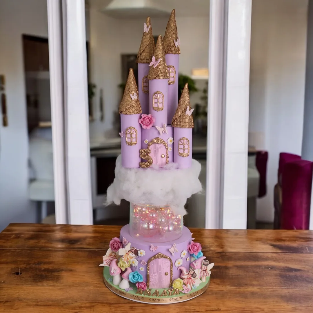 Pink castle theme cake with gold towers and floral details