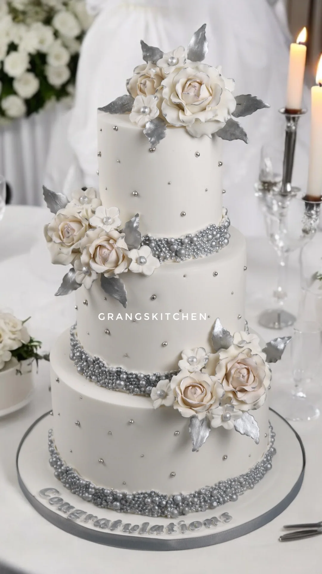 White wedding cake with silver pearl details and sugar flowers