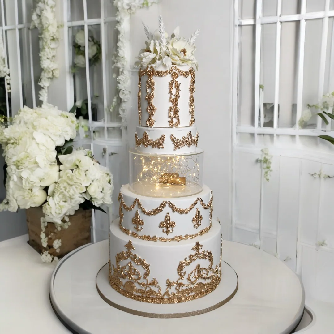 Tall white and gold wedding cake with illuminated floral centre tier