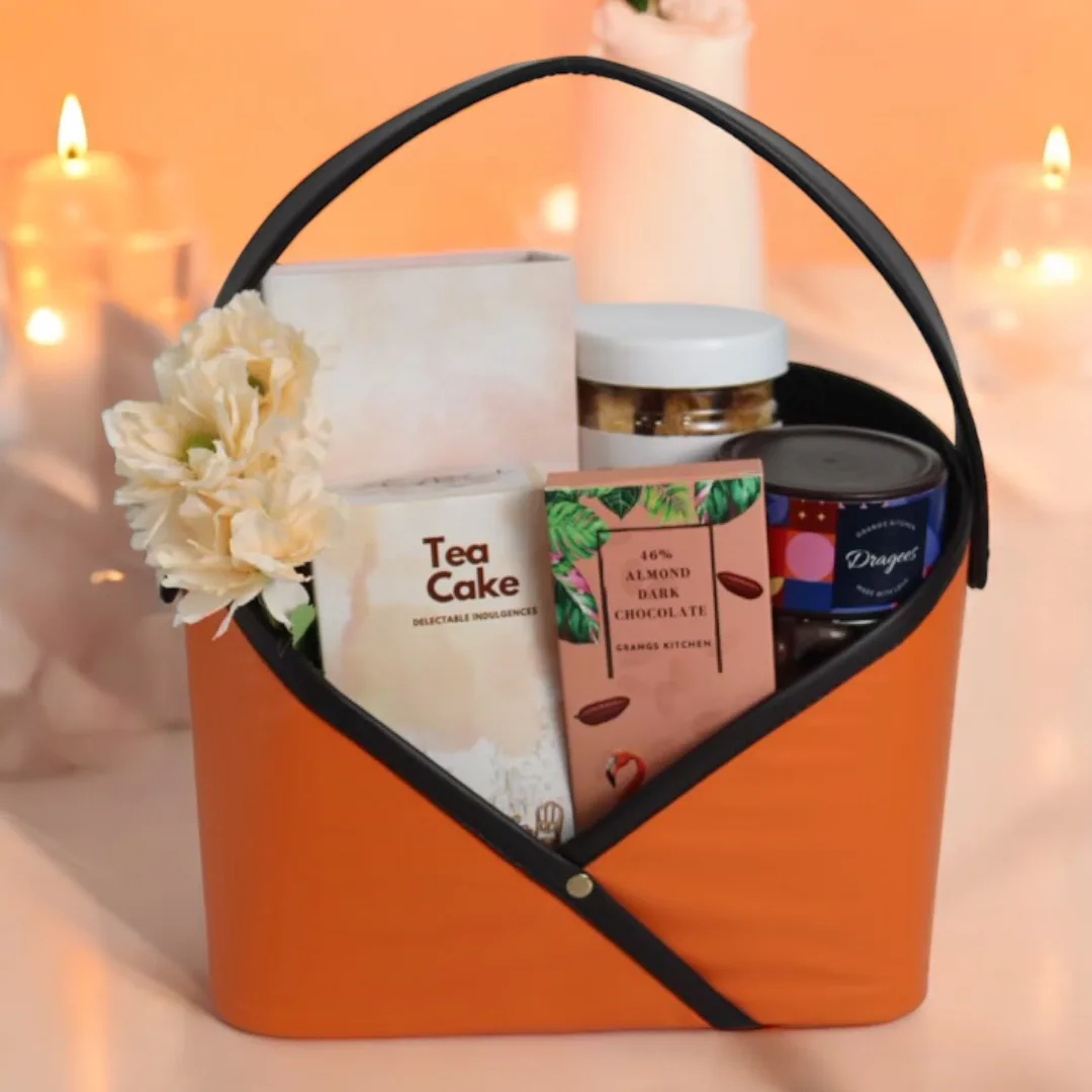 Orange Diwali gift basket with tea cake, chocolate and festive flowers